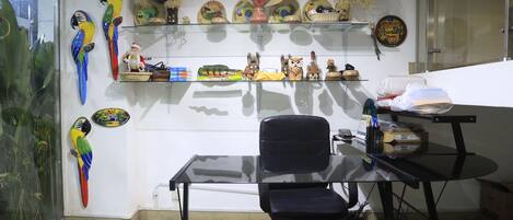 A room with a glass desk, a black office chair, and shelves with decorative items.