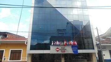 A hotel with a modern glass facade, a Best Western Plus sign, and multiple flags displayed outside.