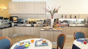 Una cucina moderna con isola centrale, dotata di macchina per il caffè, bottiglie di vino e diverse opzioni per la colazione.