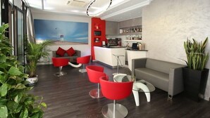 Un'area lounge moderna con un bar, sedie rosse e bianche e un divano grigio.