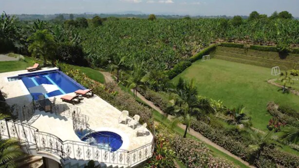 Una villa lujosa con piscina, rodeada de exuberante vegetación y un jardín bien cuidado.