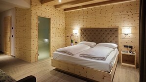 Une pièce aux murs lambrés, avec un lit, une table de chevet et une petite fenêtre.