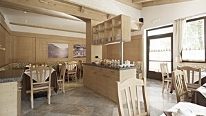 Un vaste espace à manger aménagé avec des meubles en bois et un îlot central, de grandes fenêtres avec des rideaux et une vue sur l’extérieur.