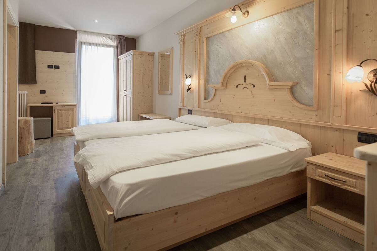 A hotel room with a large bed, wooden headboard, and a small desk.