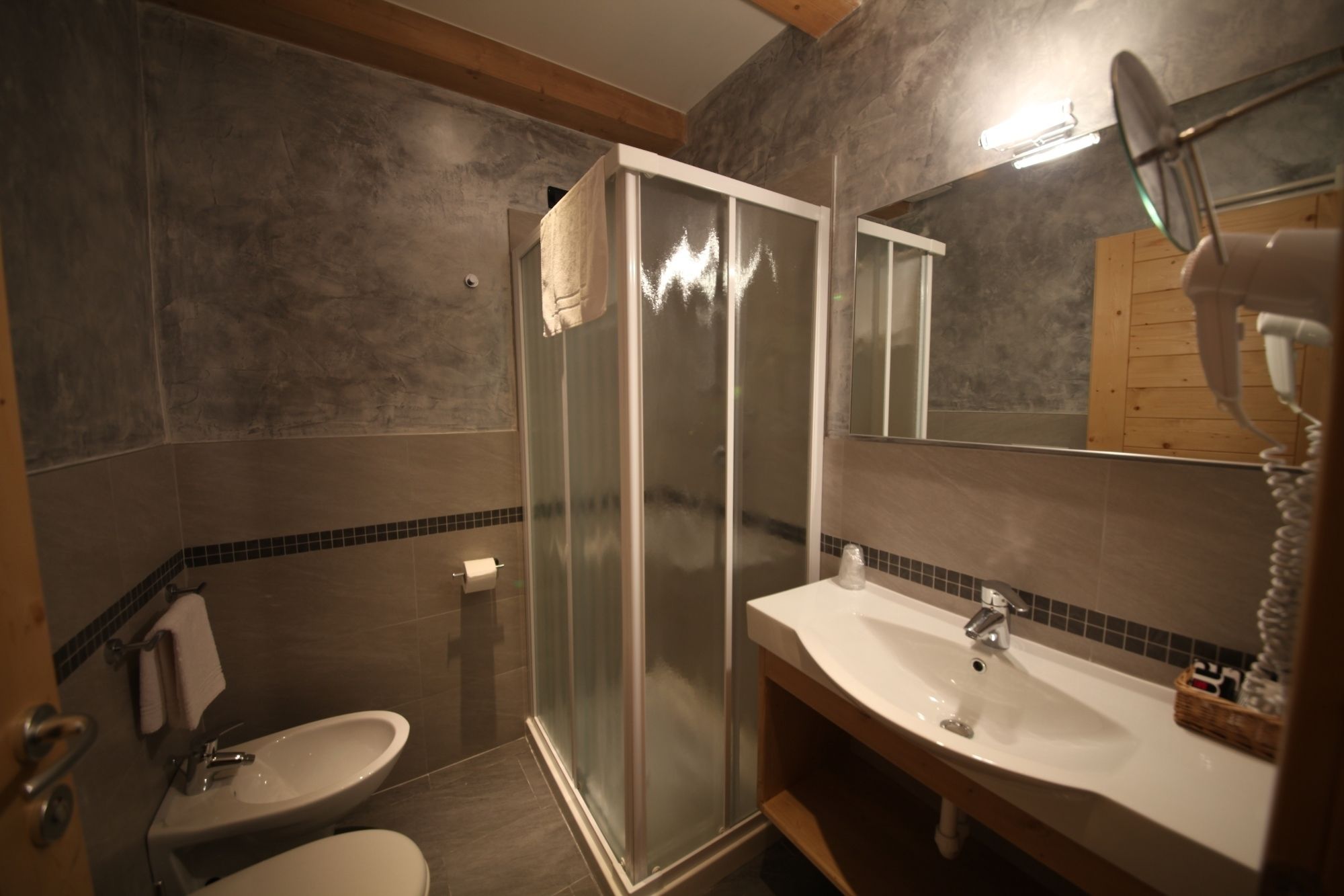 Et badeværelse med glasbrusekabine, vask og toilet.