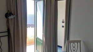 Une pièce dotée d’une porte coulissante donnant sur un balcon, d’une chaise et d’une petite table.