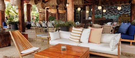 An outdoor seating area with wicker furniture, a wooden coffee table, and hanging wicker lamps.