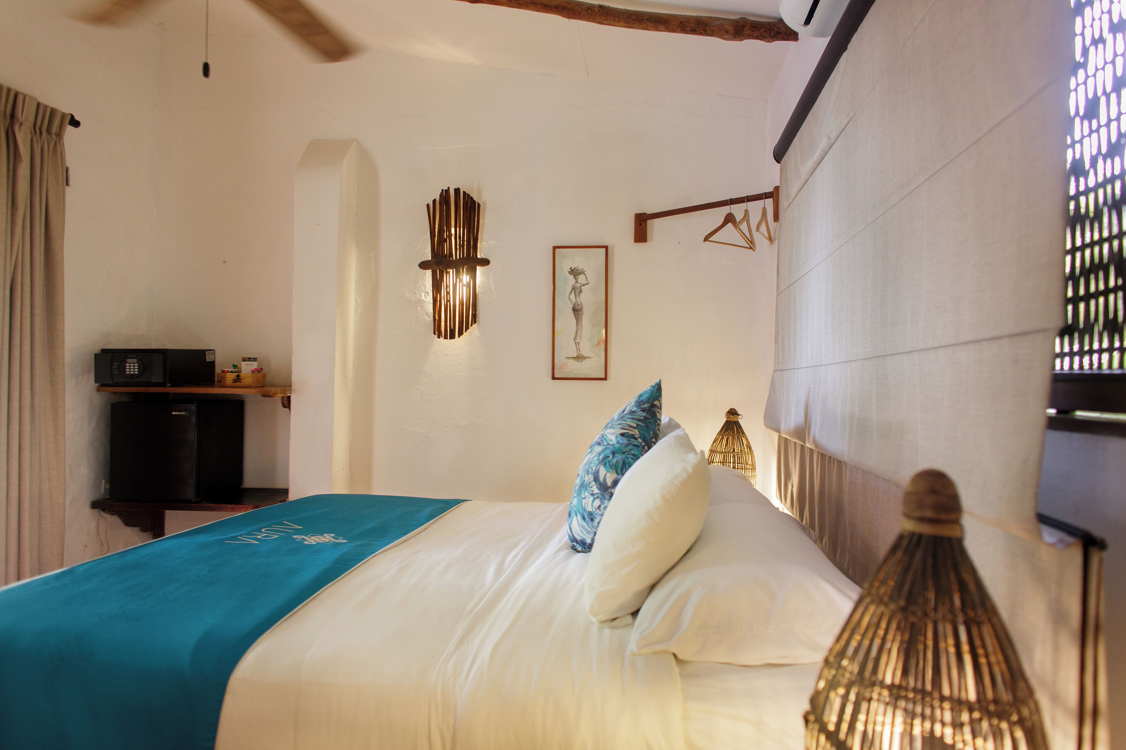 A bedroom with a bed, a bedside table, a hanging light fixture, and a wall-mounted picture.
