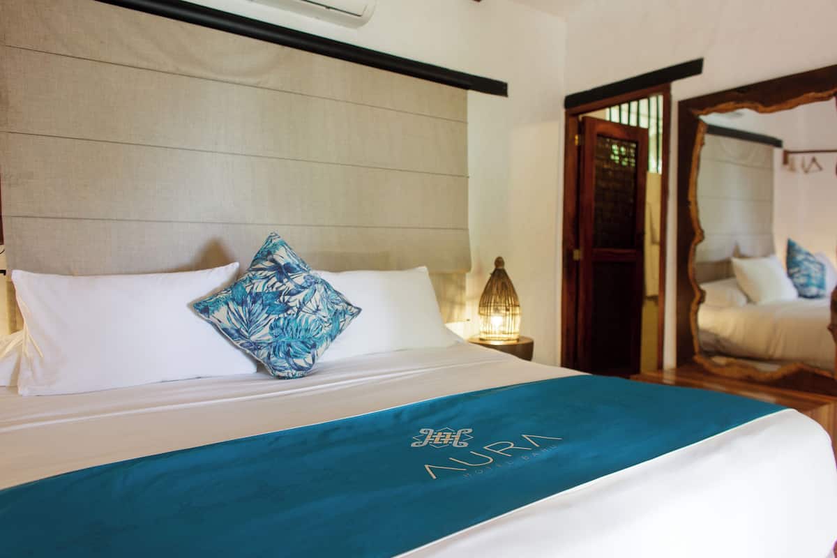 A hotel room with a bed, a nightstand, and a mirror.