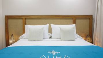 A hotel room with a wooden headboard, white bedding, and a blue bedspread with the hotel logo.