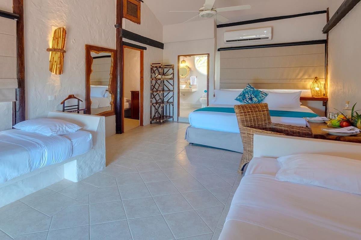 A hotel room with two beds, a ceiling fan, and a view of the beach.