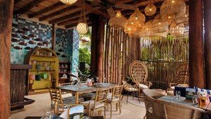 Een restaurant met houten meubels, hangende rieten lampen en een muur met vismotieven.