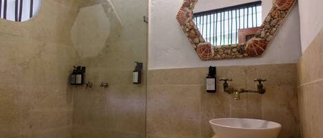 A bathroom with a shower, a sink, and a mirror with a shell border.