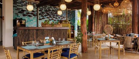 A restaurant with wooden tables and chairs, hanging lights, and a fish wall.