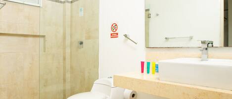 Un baño moderno con ducha de vidrio, inodoro blanco y piso de baldosas color beige.
