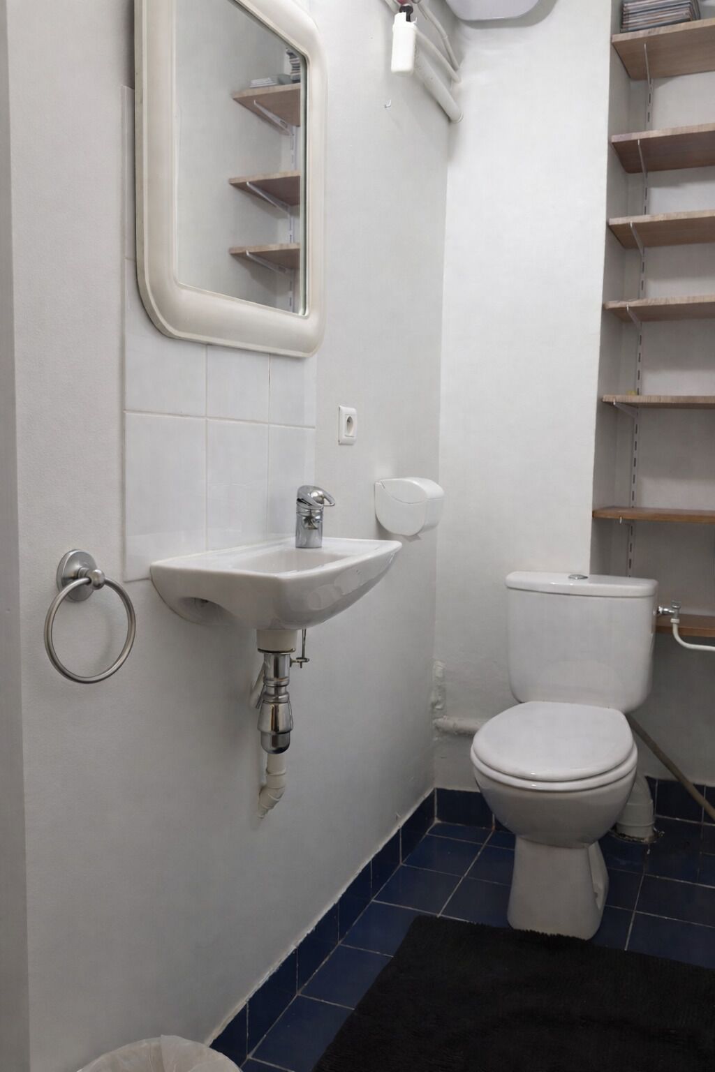 A bathroom with a white sink, a toilet, and a mirror.
