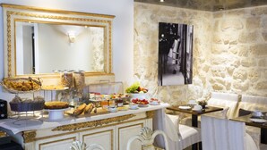 Un bufé de desayuno con diversos alimentos y un fondo de pared de piedra.