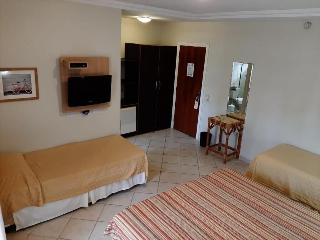 Una habitación con dos camas, televisión, armario y espejo.