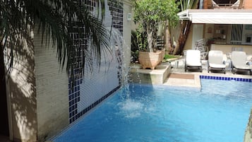 Una piscina techada, una piscina al aire libre, sombrillas