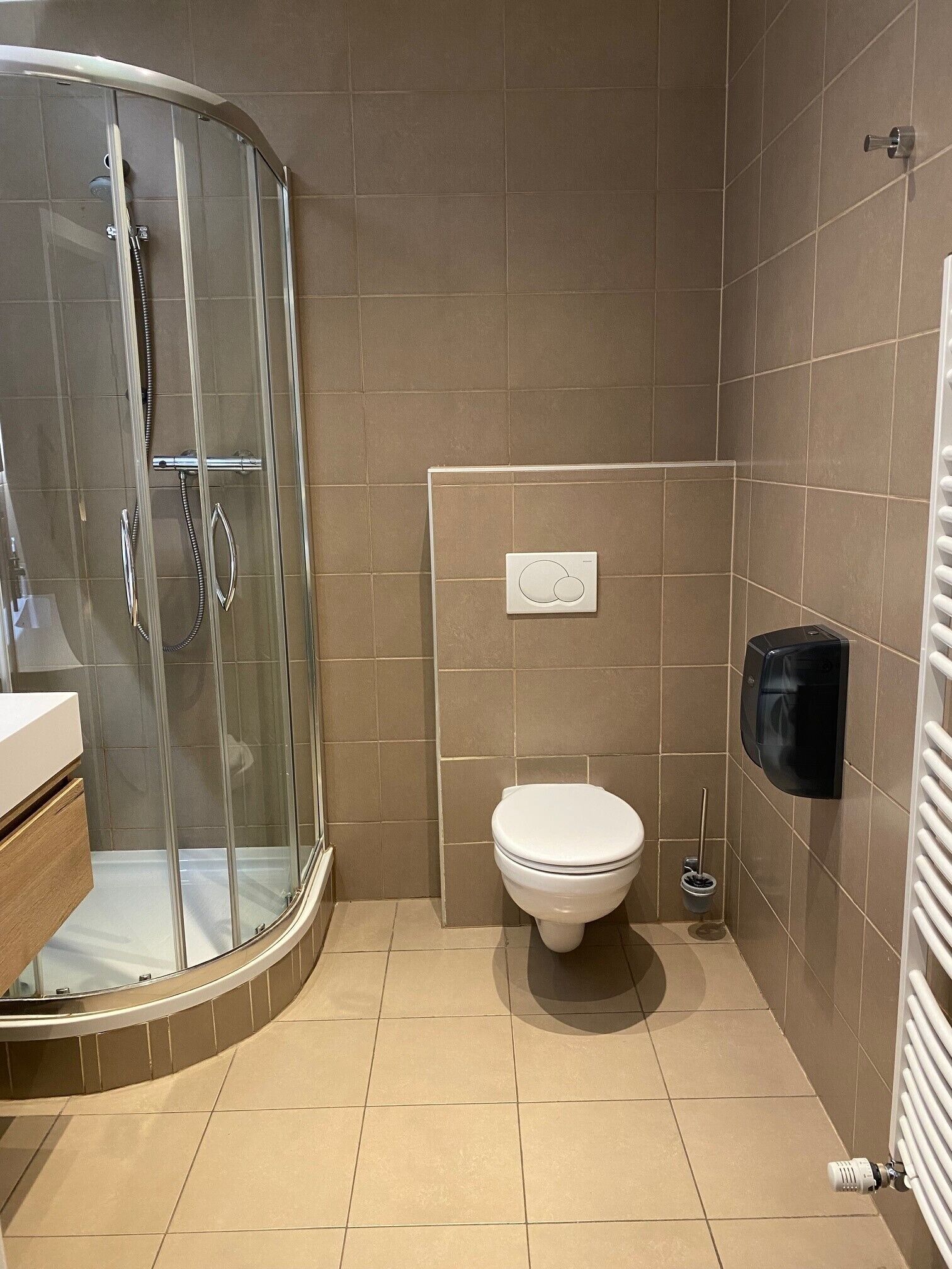 Un baño con cabina de ducha de vidrio, inodoro y secador de manos.