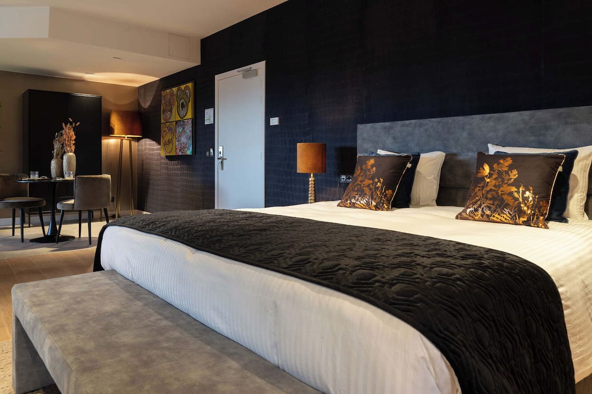 A modern hotel room with a large bed, a desk, and a chair.