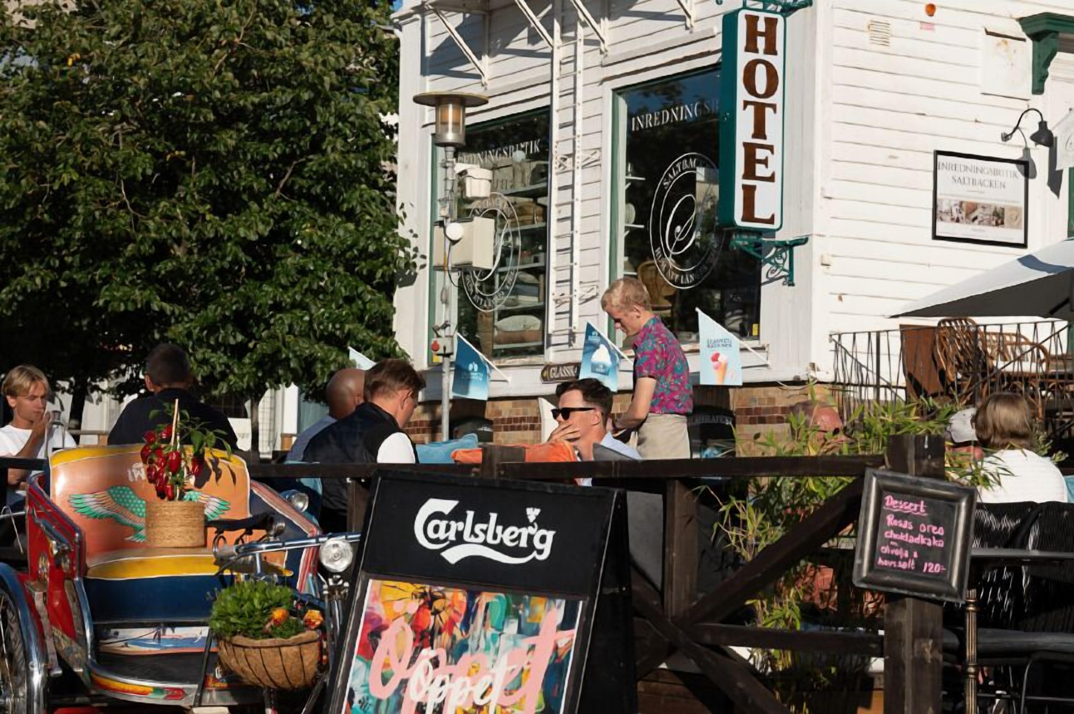 Un hôtel avec une enseigne indiquant « HÔTEL » et un panneau publicitaire pour la bière « Carlsberg ».