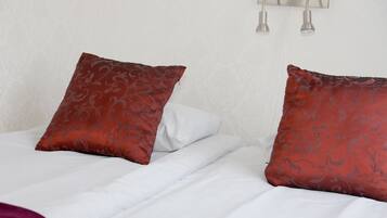 A neatly made bed with white linens and two decorative pillows with a floral pattern.
