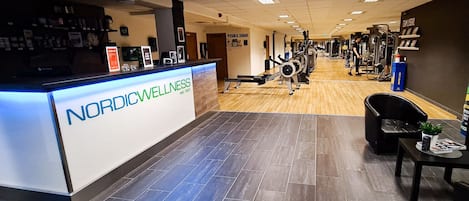 A gym with a reception desk labeled "Nordic Wellness" and various exercise equipment.
