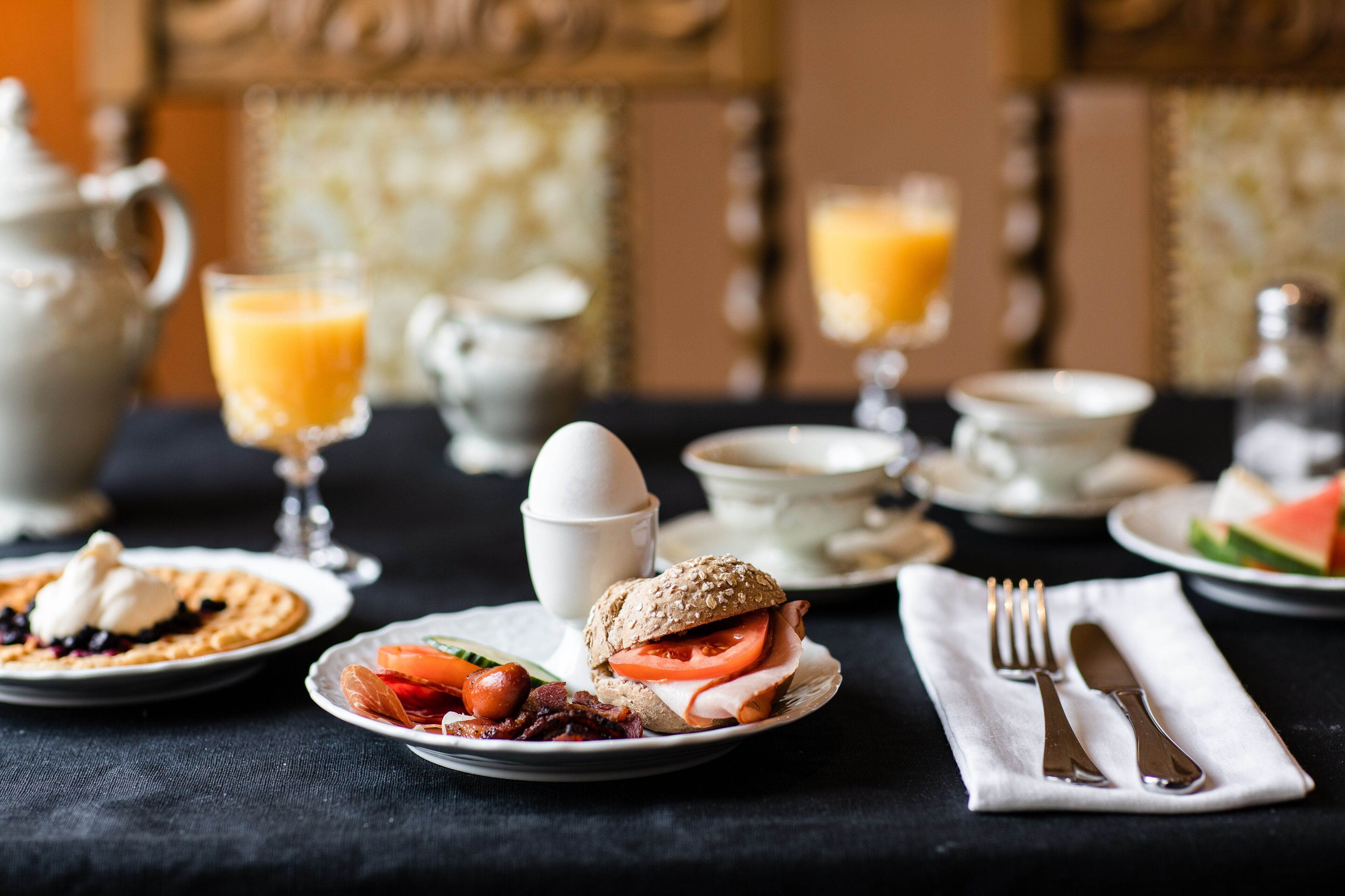 A breakfast setting with plates of food, a cup of coffee, and a glass of orange juice.