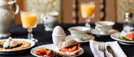 A breakfast setting with plates of food, a cup of coffee, and a glass of orange juice.