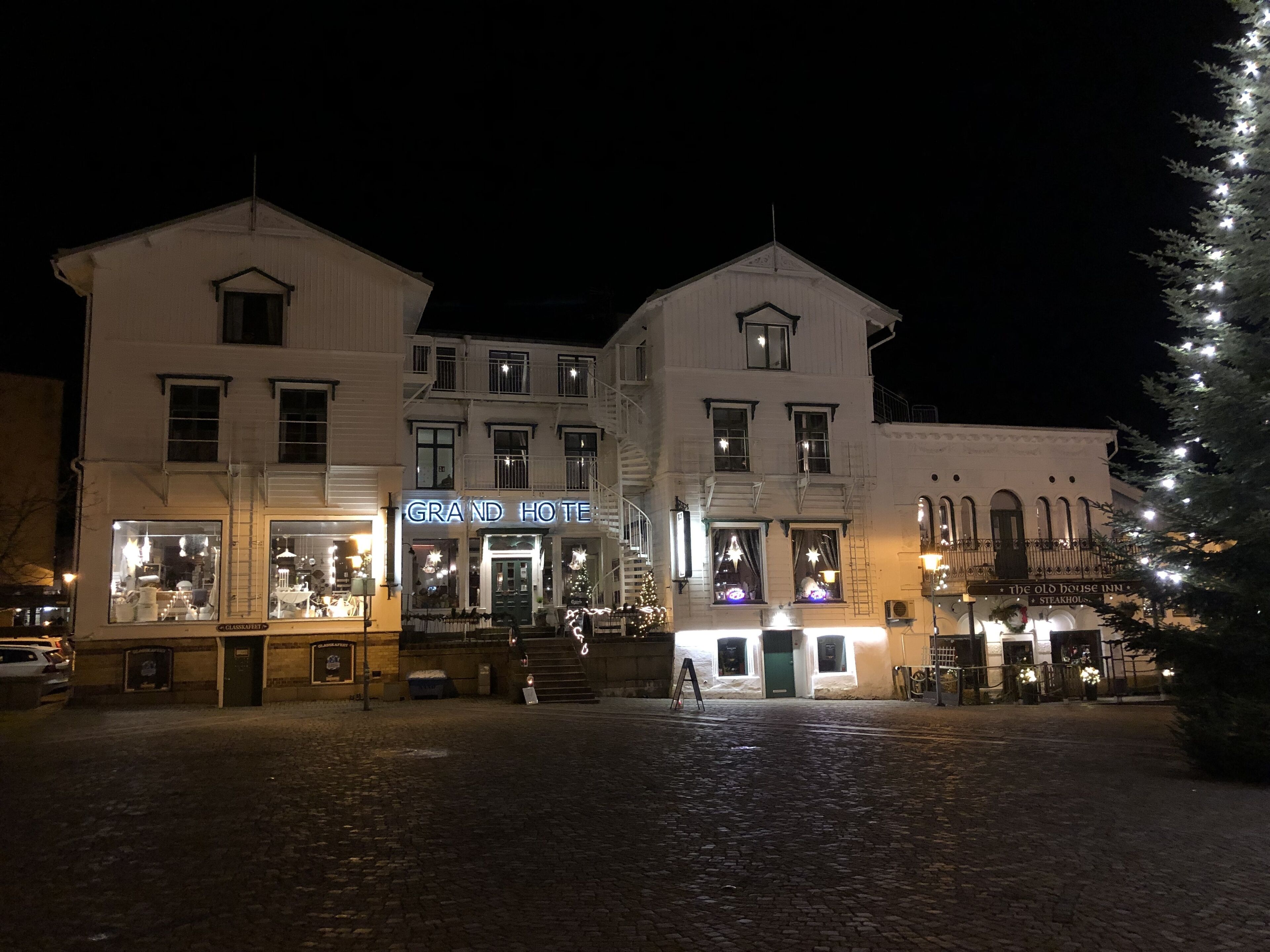 A historic building with a prominent 'Grand Hotel' sign, a cobblestone courtyard, and a Christmas tree.
