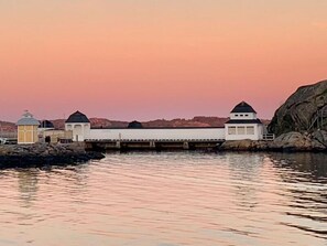 A waterfront building with multiple structures, including a lighthouse and a white building with a black roof. - Grand Hotel Lysekil (Lysekil)