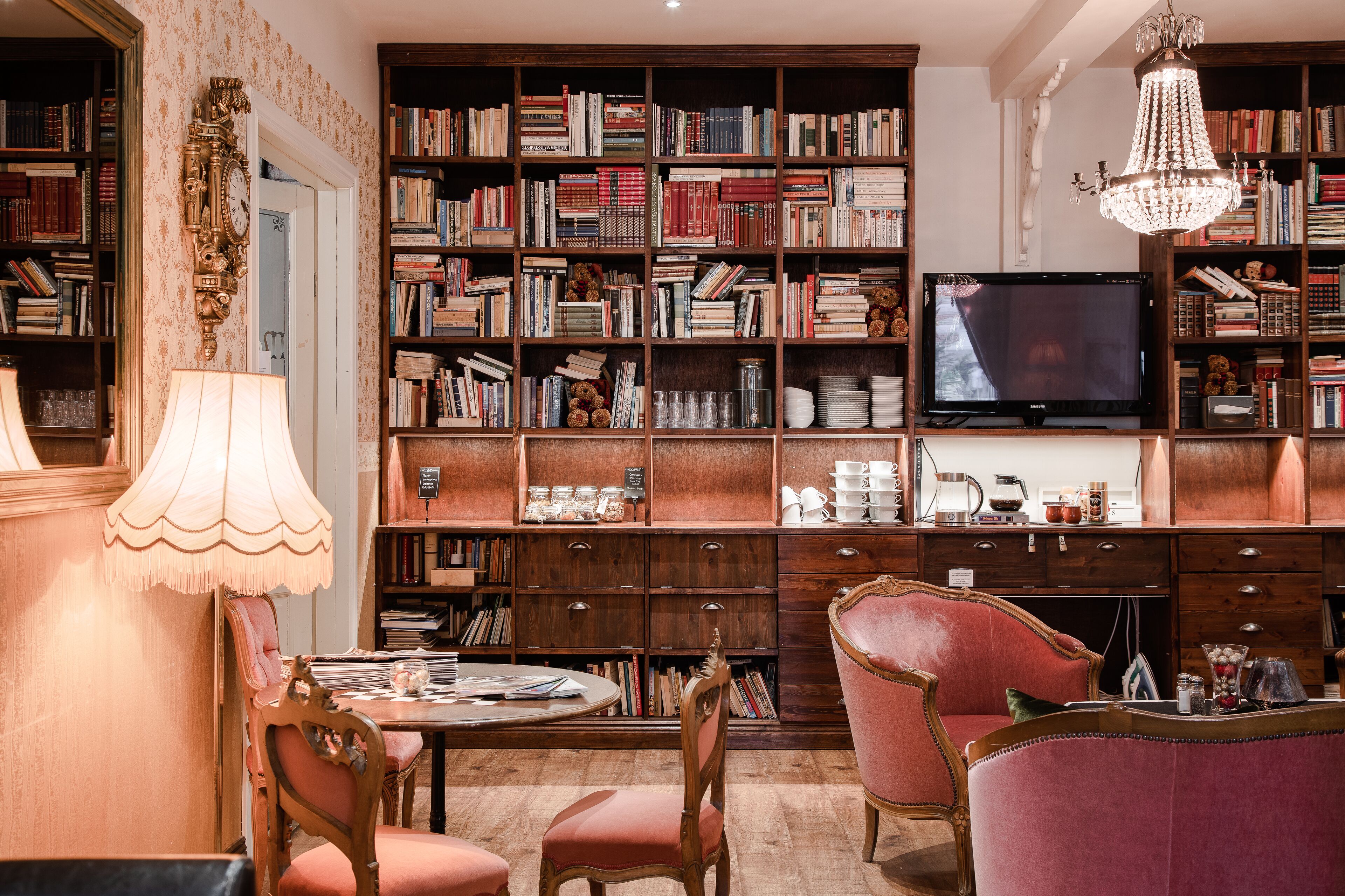 A library with bookshelves, a television, and a chandelier.