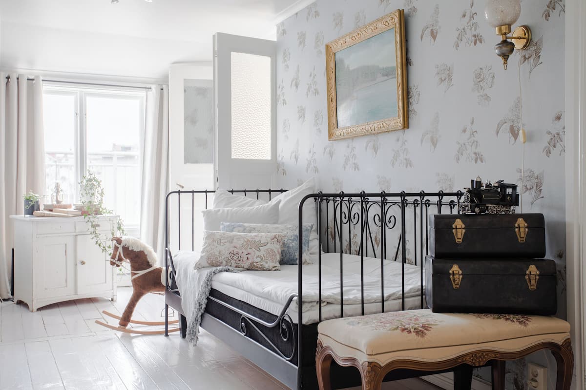 Une chambre à coucher avec un lit, un cheval à bascule, une commode et une valise.