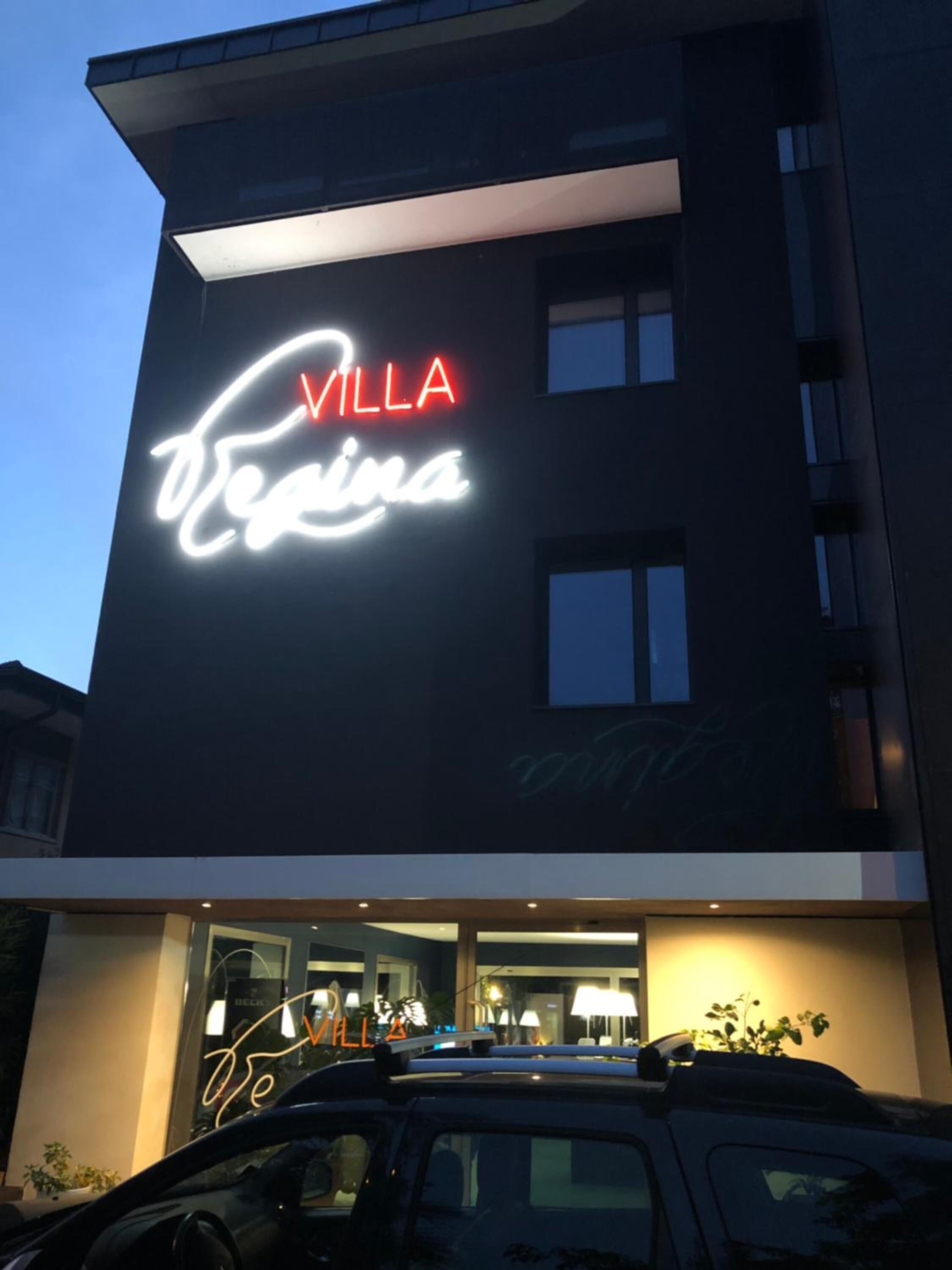 Un bâtiment moderne doté d’une enseigne lumineuse bien visible, sur laquelle on peut lire : « VILLA Verina ».