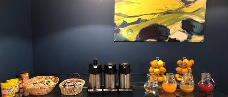 Uma mesa com alimentos e acompanhamentos, um quadro na parede e uma luminária pendente.
