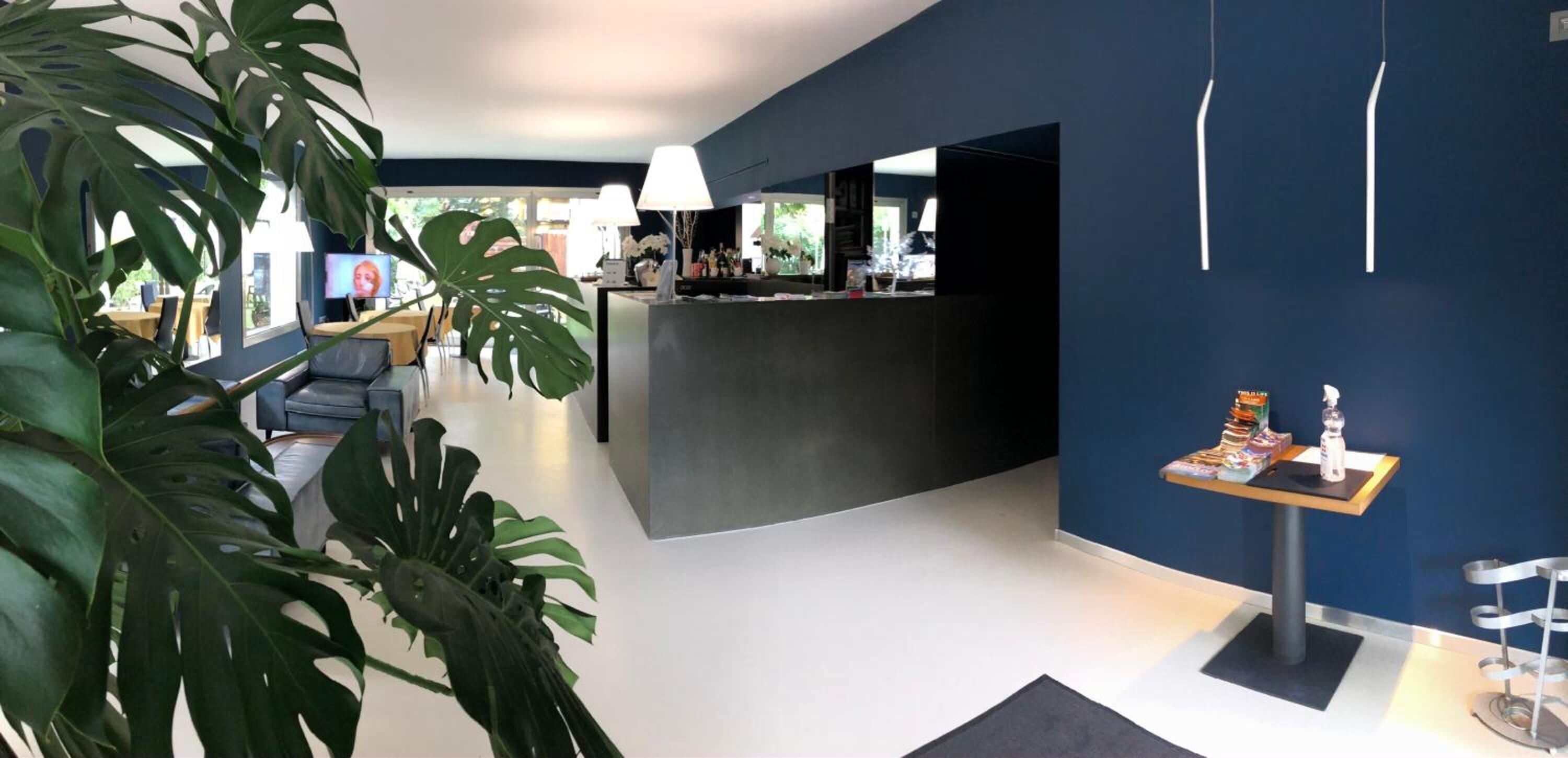 A modern interior with a reception desk, seating area, and large plants.