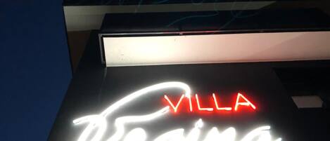 Un edificio con un letrero de neón que dice "VILLA" en rojo y "Repina" en blanco.