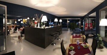 Un comedor moderno con una isla central, varias mesas y sillas. Se ve un perro en primer plano.