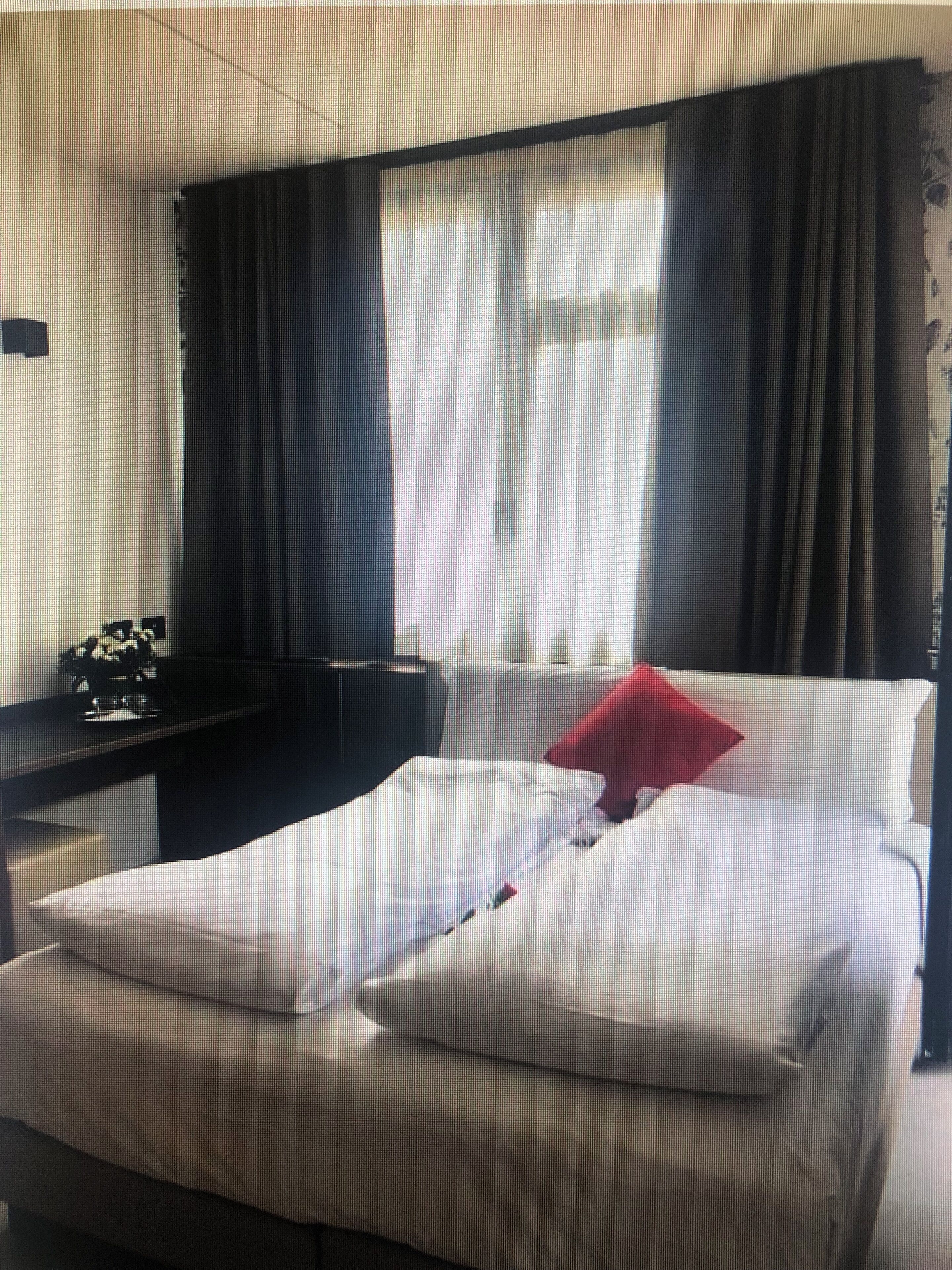 A hotel room with a bed, a desk, and a window with curtains.