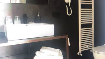 Un baño con pared oscura, un lavamanos blanco, un perchero y un inodoro.