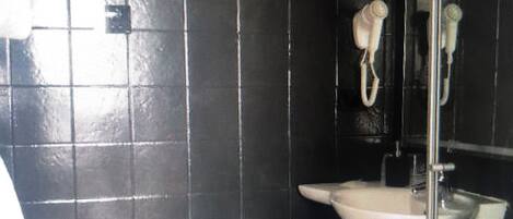 A bathroom with a black tiled wall, a white sink, a mirror, and a hanging towel.