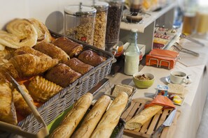 A buffet with various breads, pastries, and condiments.