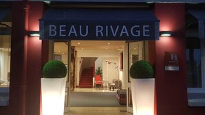 The entrance to a hotel named "BEAU RIVAGE" with a modern design, featuring a staircase leading to the interior, and two potted plants at the entrance. - Hôtel Beau Rivage (Argelès-sur-Mer)