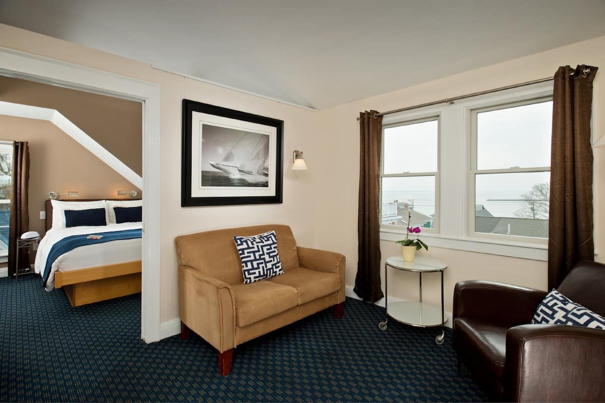 A hotel room with a bed, a sofa, a small table, and a window with curtains.