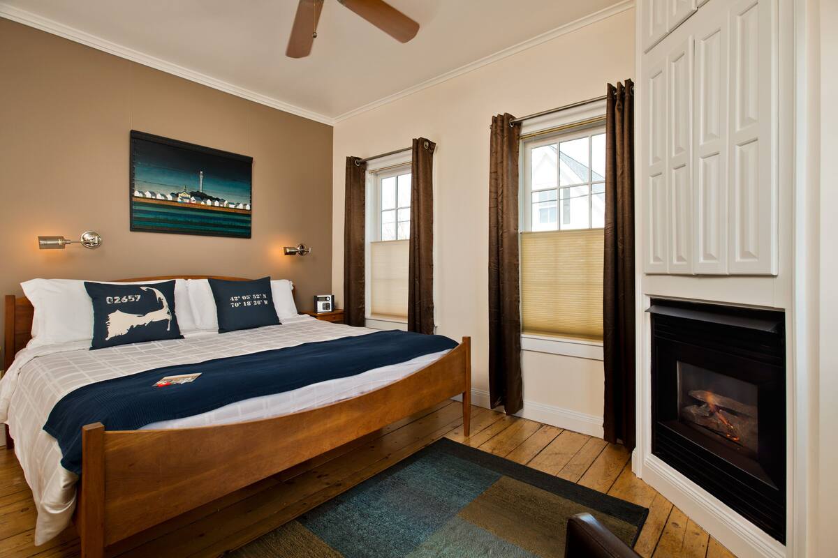 A bedroom with a wooden bed, a fireplace, and a painting on the wall.
