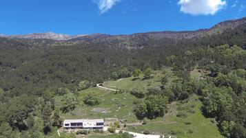 A modern building with a flat roof, surrounded by a lush green landscape with a winding path.