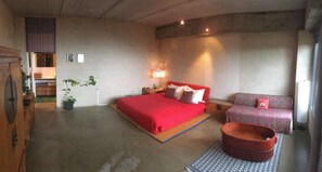 A bedroom with a large bed, a sofa, a wooden tub, and a patterned rug. - Hotel La Canela (Piedralaves)