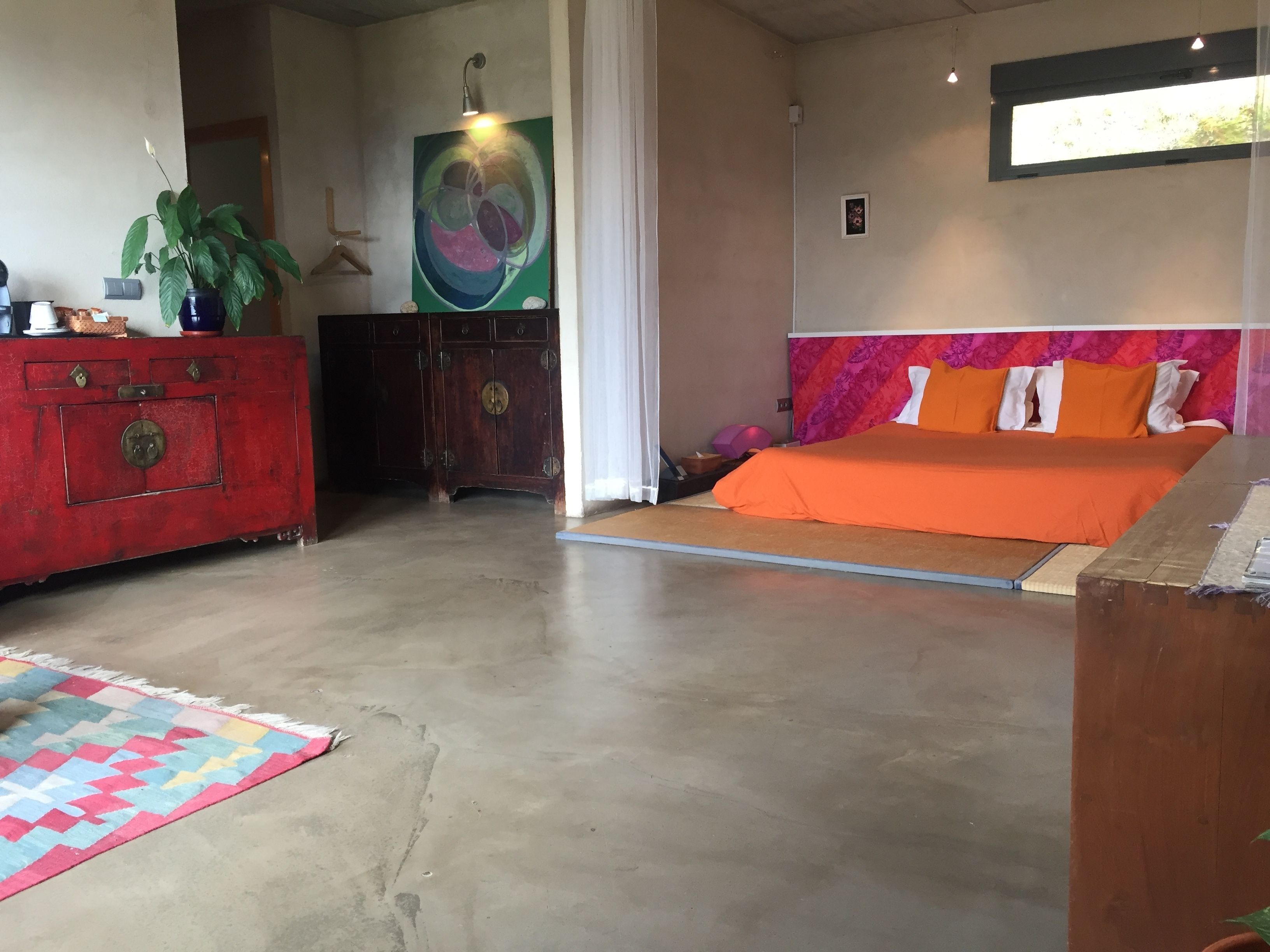 Un dormitorio con una cama, un aparador, un cuadro y una planta.