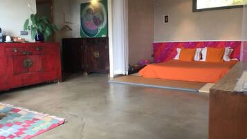 Un dormitorio con una cama, un aparador, un cuadro y una planta.